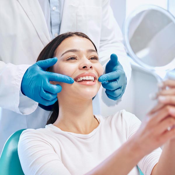 woman looking at smile in mirror in dental chair